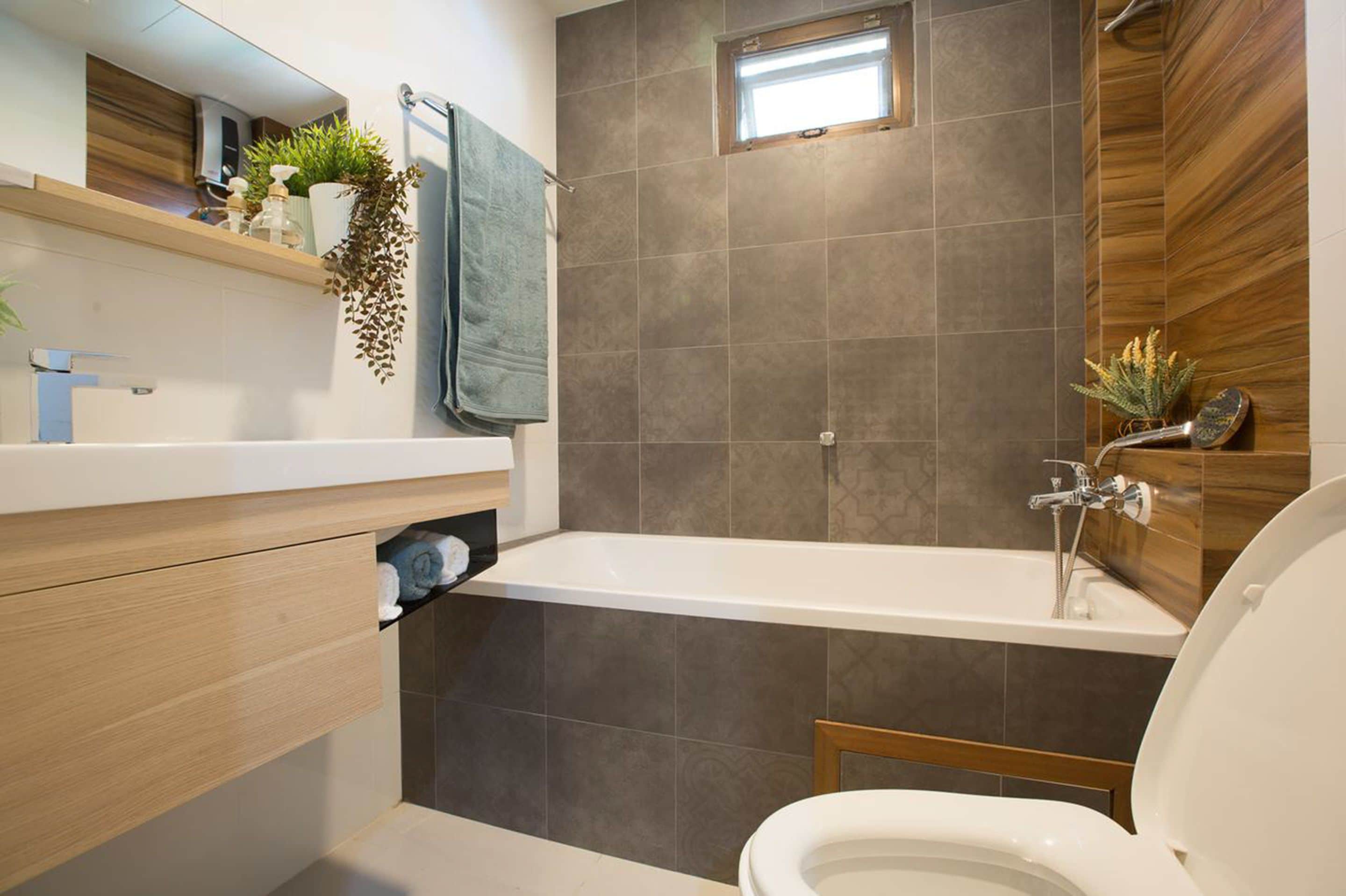A modern bathroom with a bathtub, toilet, and a shelf with plants.