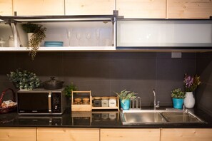 Una cocina moderna con encimera negra, pileta de acero inoxidable y armarios de madera.