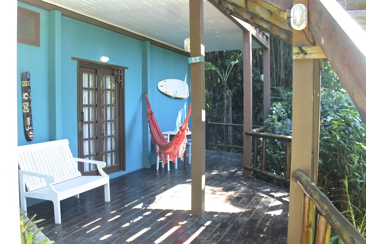 A covered porch with a white bench, a hammock, and a wooden railing.