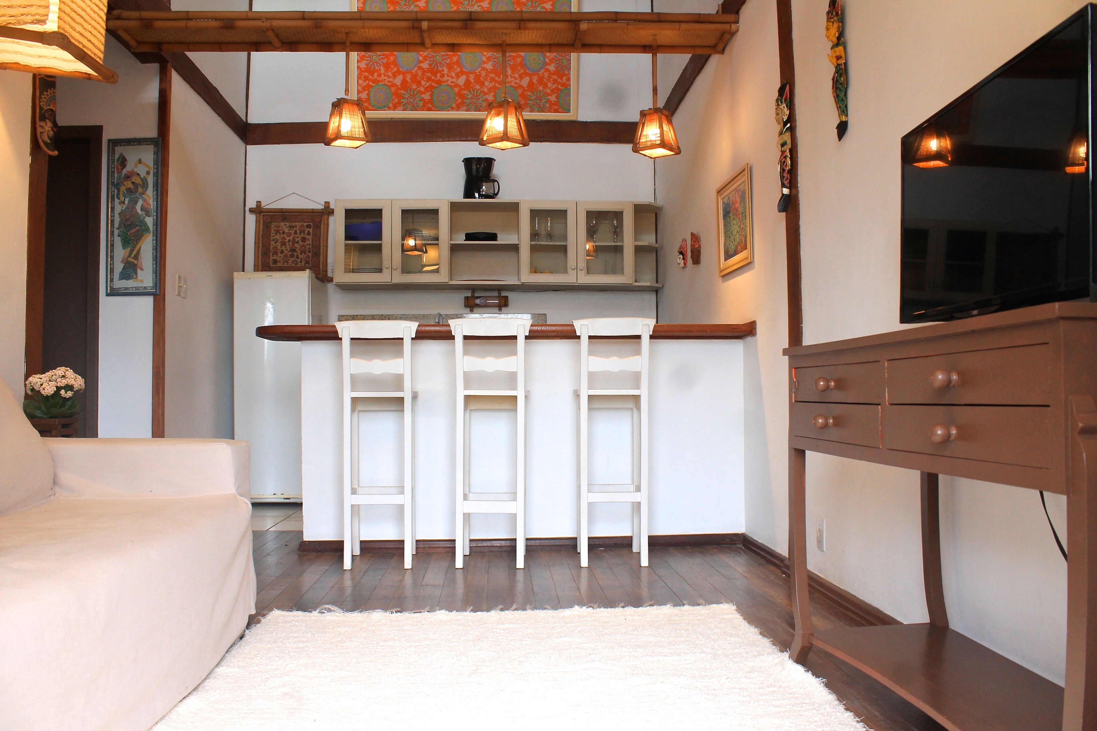 A kitchen with white cabinets, a wooden countertop, and a TV mounted on the wall.