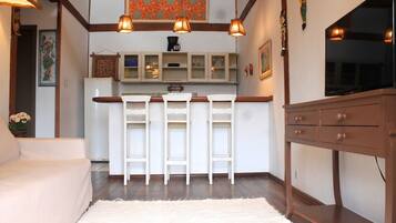 A kitchen with white cabinets, a wooden countertop, and a TV mounted on the wall.