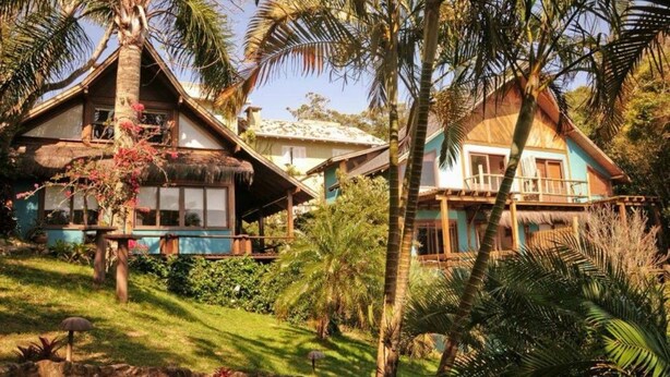 Un resort tropical con cabañas de techo de paja, exuberante vegetación y un cielo despejado.