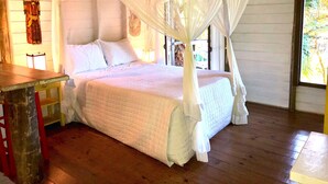 Una cama con dosel, suelo de madera y una pared rústica con un adorno.