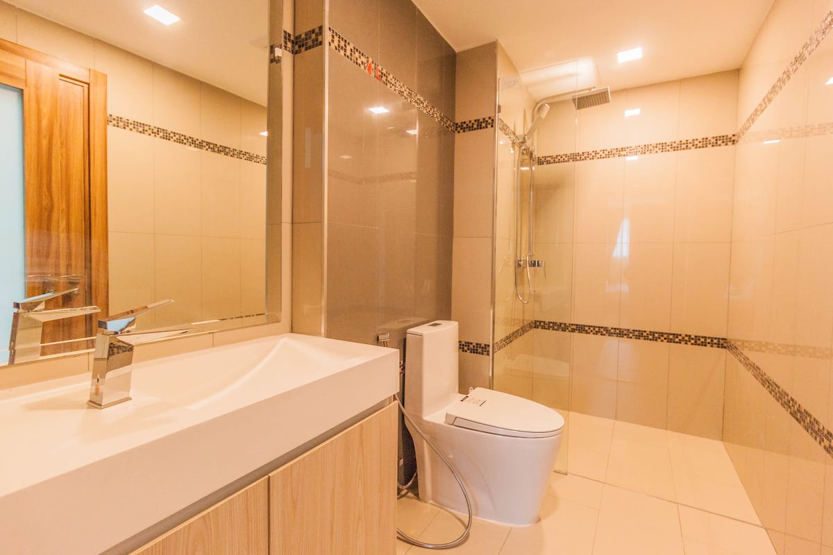 A modern bathroom with a large mirror, a sink, a toilet, and a shower area.