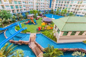Un espace piscine d’hôtel comprenant un toboggan aquatique, des jeux et une aire de jeux pour enfants.
