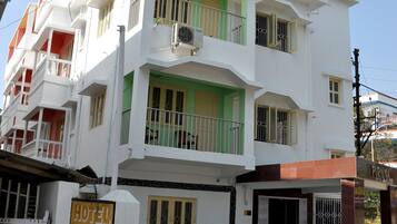 A multi-story hotel with balconies, a gated entrance, and a sign indicating it is the Hotel Purnima.