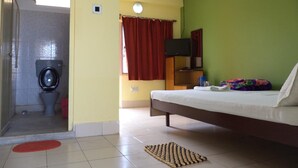 Una camera con un letto, una televisione, un bagno con il water e una doccia, e una tenda rossa.