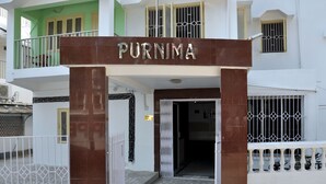 L'ingresso di un edificio con un cartello che riporta 'PURNIMA' e un tappetino con la scritta 'WELCOME'.