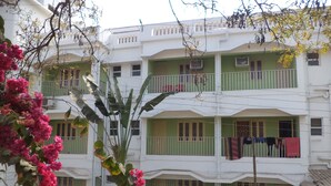 Un edificio a più piani con balconi, un recinto bianco e un albero con fiori rosa.