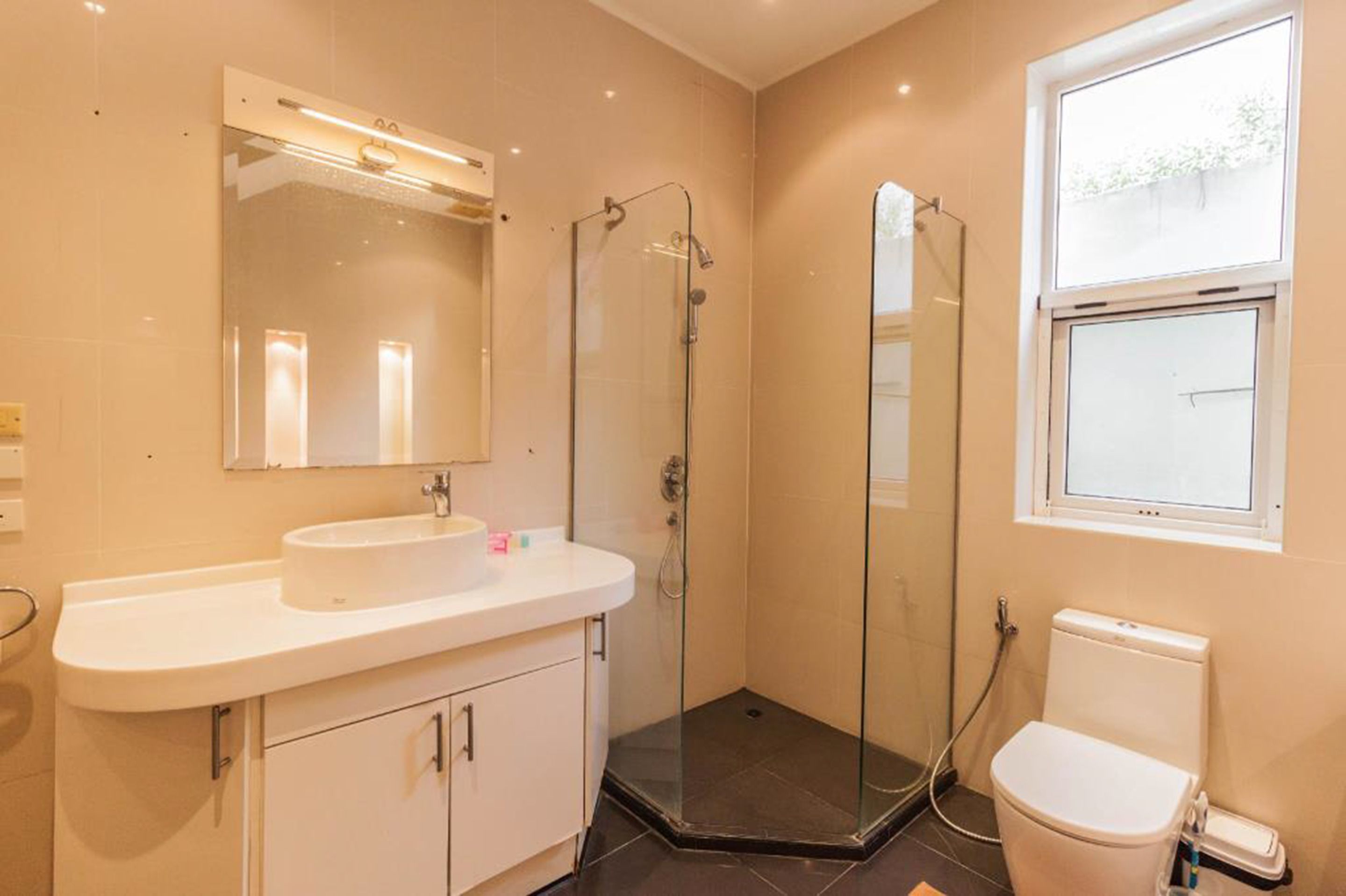 A modern bathroom with a glass-enclosed shower, a white sink, and a toilet.