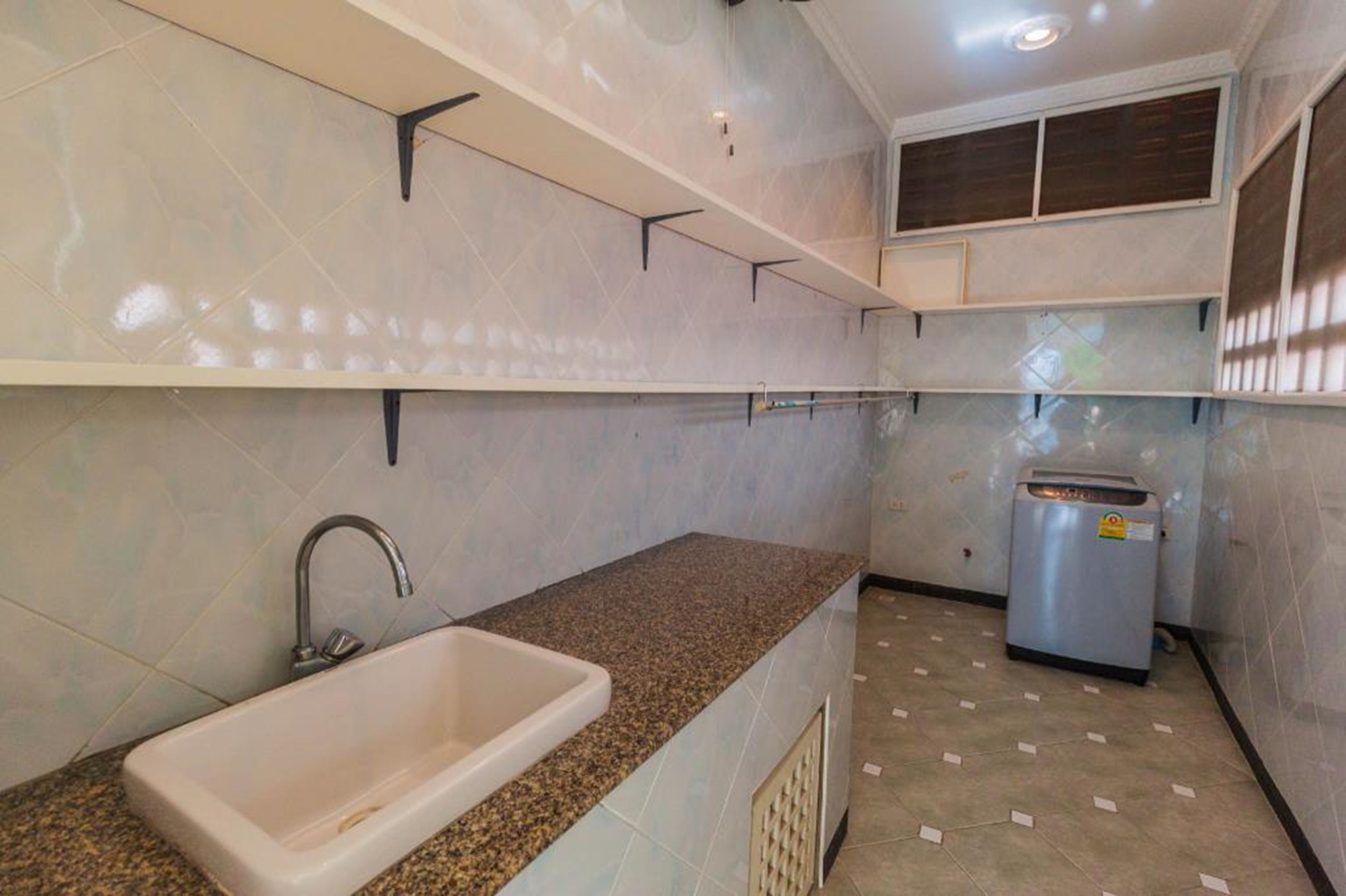 Una cocina compacta con encimera de granito, un lavabo y un refrigerador empotrado.