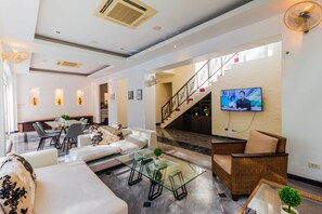 A modern living room with a glass coffee table, sofas, and a television mounted on the wall.