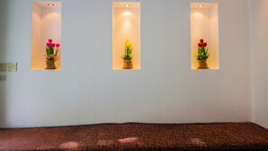 Trois niches murales éclairées, ornées de plantes et de fleurs en pot.