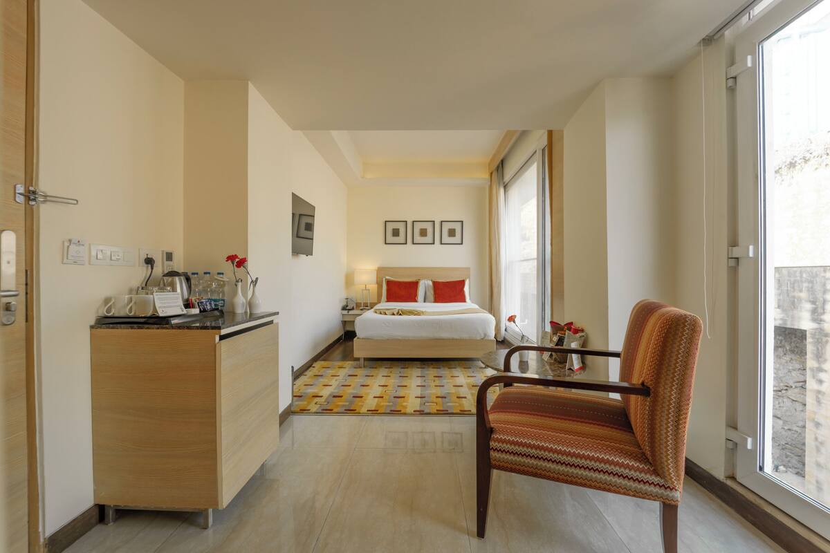 Ein Hotelzimmer mit Bett, Schreibtisch, Stuhl und Fenster.
