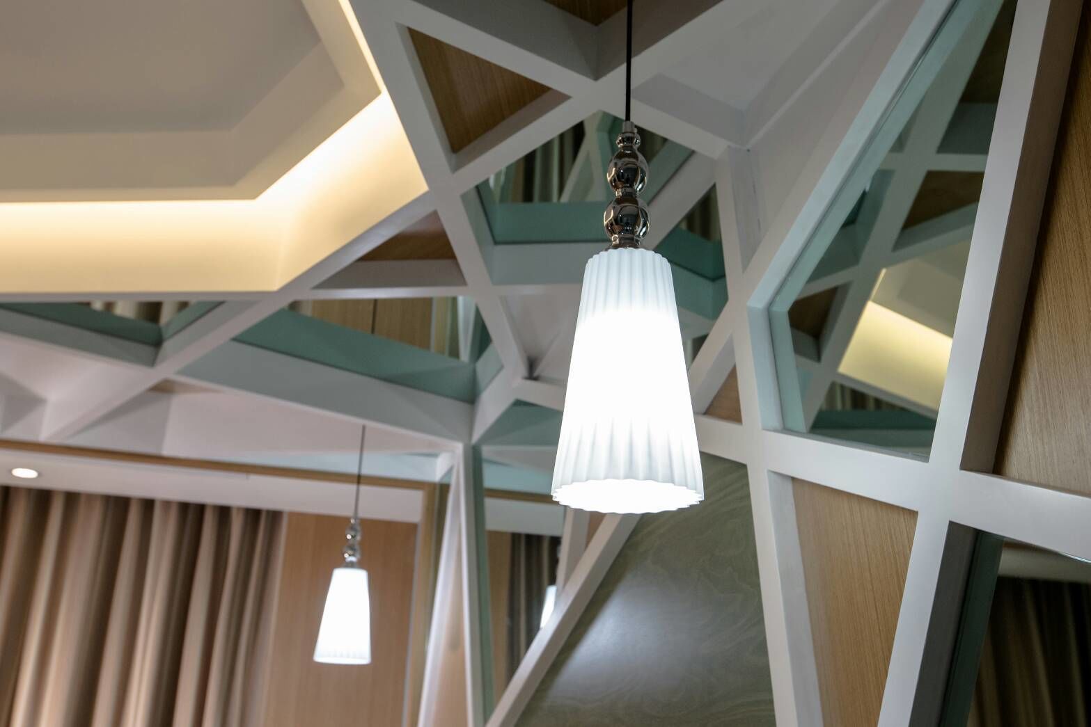 Un interior moderno con diseño geométrico en el techo, lámparas colgantes y una escalera visible.