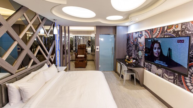 Une chambre d’hôtel moderne, dotée d’un grand lit, d’un bureau et d’une télévision.