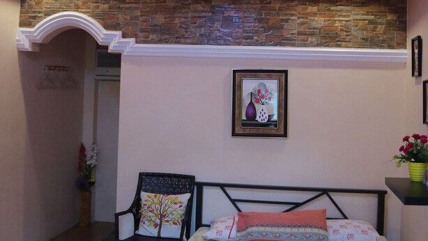 A bedroom with a bed, a chair, a wall-mounted picture, and a ceiling light. - V.Hauschild Transient House B (Alaminos)
