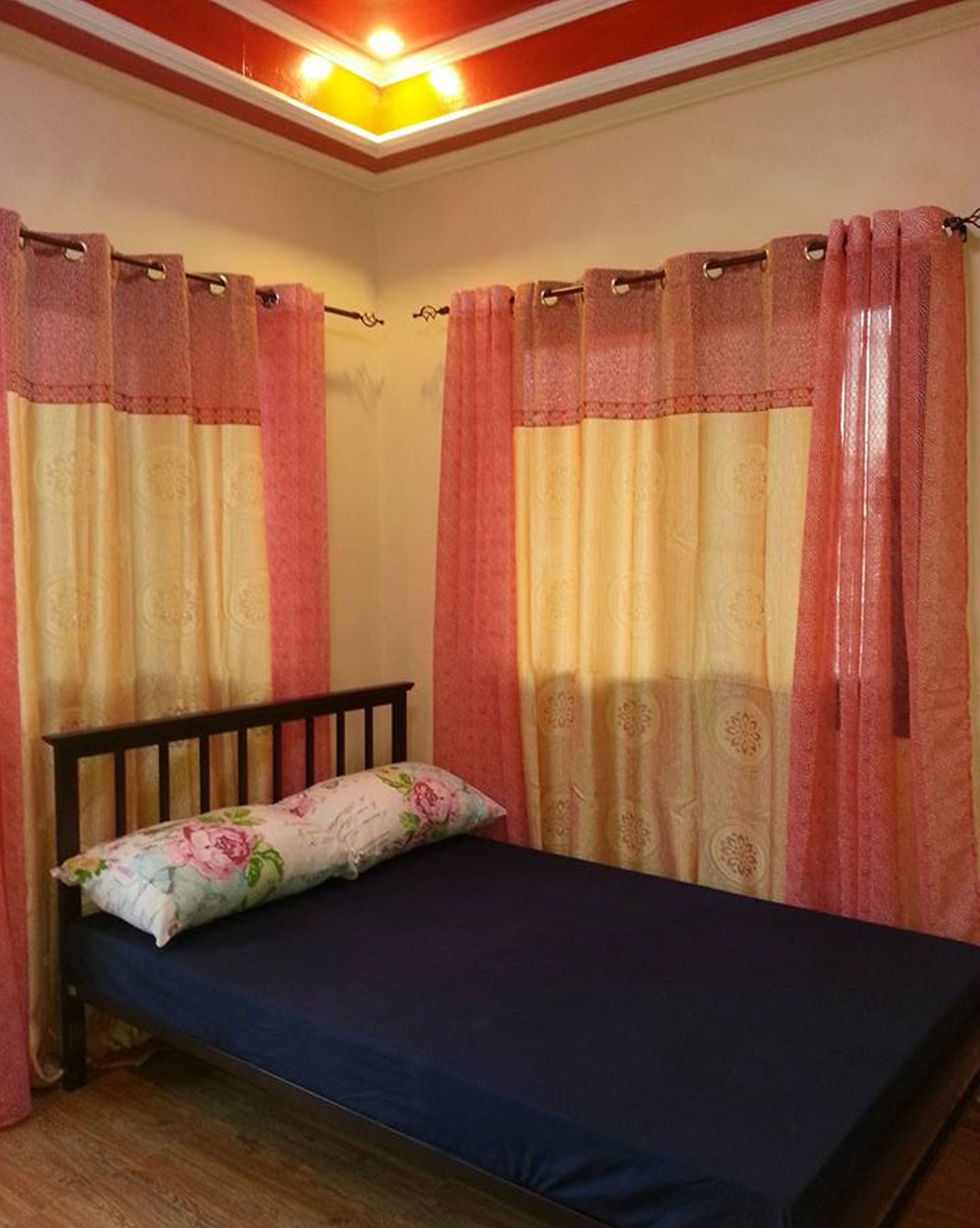 A single bed with a wooden headboard, a floral pillow, and a dark blue mattress.