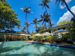 A swimming pool with clear blue water, surrounded by palm trees and lounge chairs. - Ondas Do Mar Beach Resort Phase 1 (Calangute)