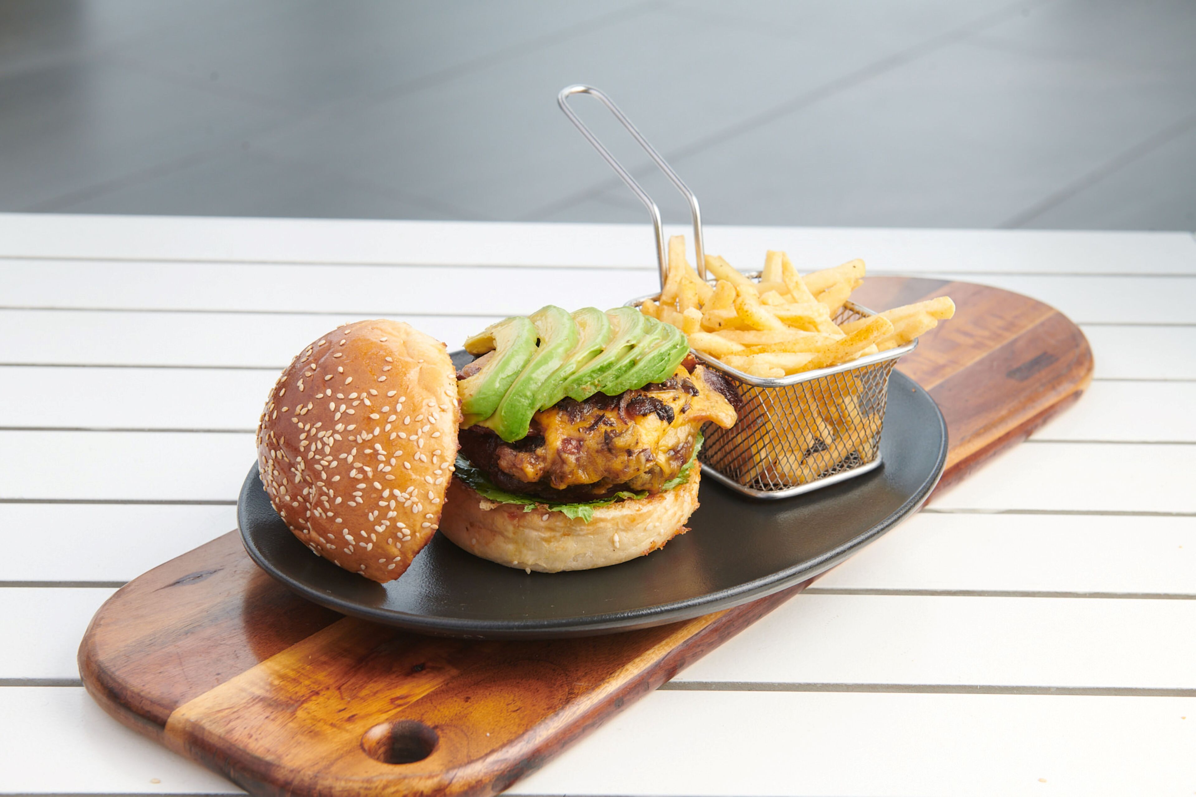 A burger with fries on a wooden board.