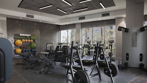 Une salle de sport moderne équipée de divers appareils d’exercice, de stations d’haltérophilie et d’un mur recouvert de ballons médicaux de couleurs vives.
