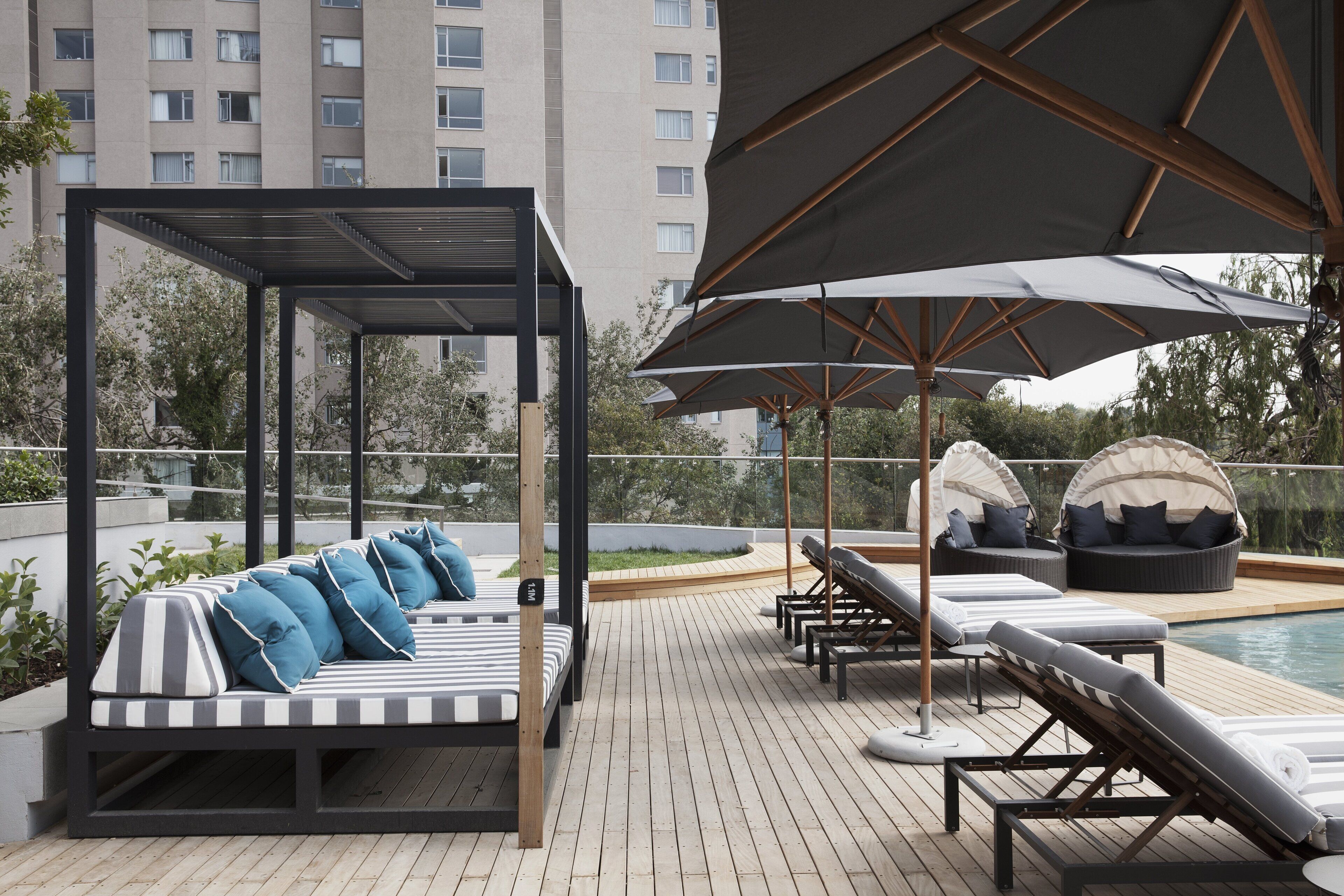 A rooftop lounge area with a covered seating area, lounge chairs, and a pool.
