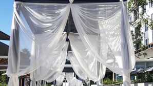 Un espace extérieur moderne, aménagé avec des sièges, un auvent et des coussins à rayures.
