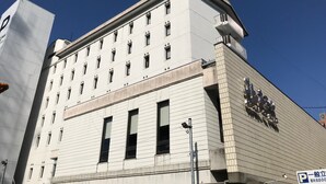 Um edifício de vários andares com fachada plana, várias janelas e uma entrada de esquina destacada.