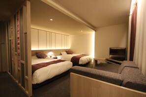 Habitación de hotel con dos camas, televisión y zona de estar.