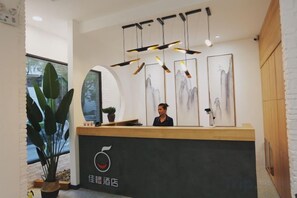 A reception desk with a black counter, a person standing behind it, and framed artwork on the wall. - Jiacheng Hotel (Xiamen Lianhua) (Xiamen)