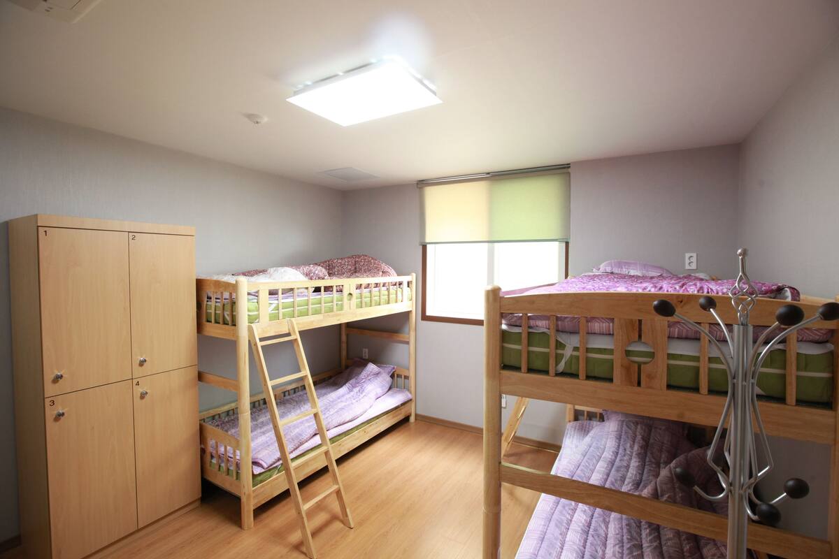 A bunk bed room with a wardrobe, a window with blinds, and a ceiling light.