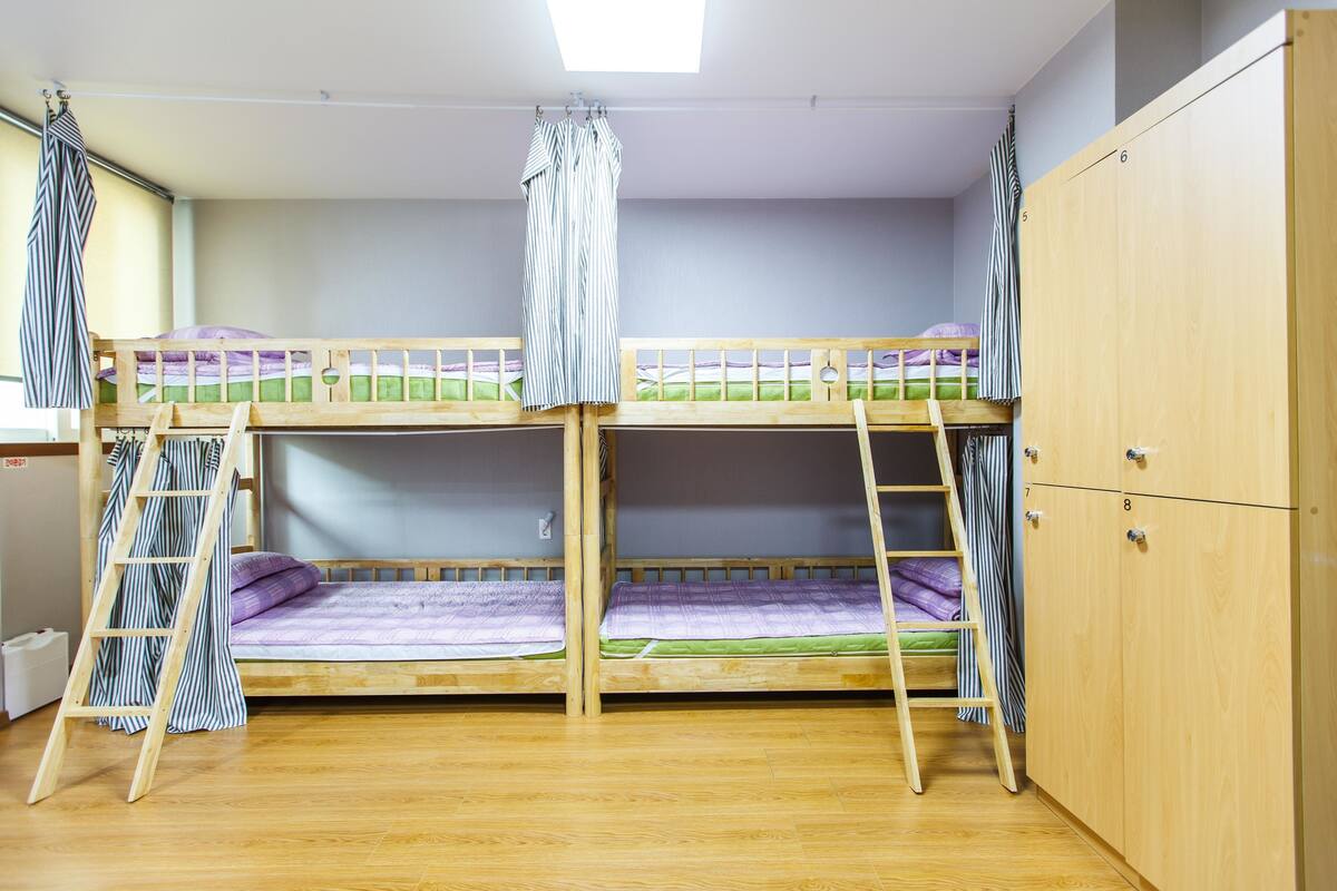 A bunk bed room with wooden flooring, a wardrobe, and a skylight.