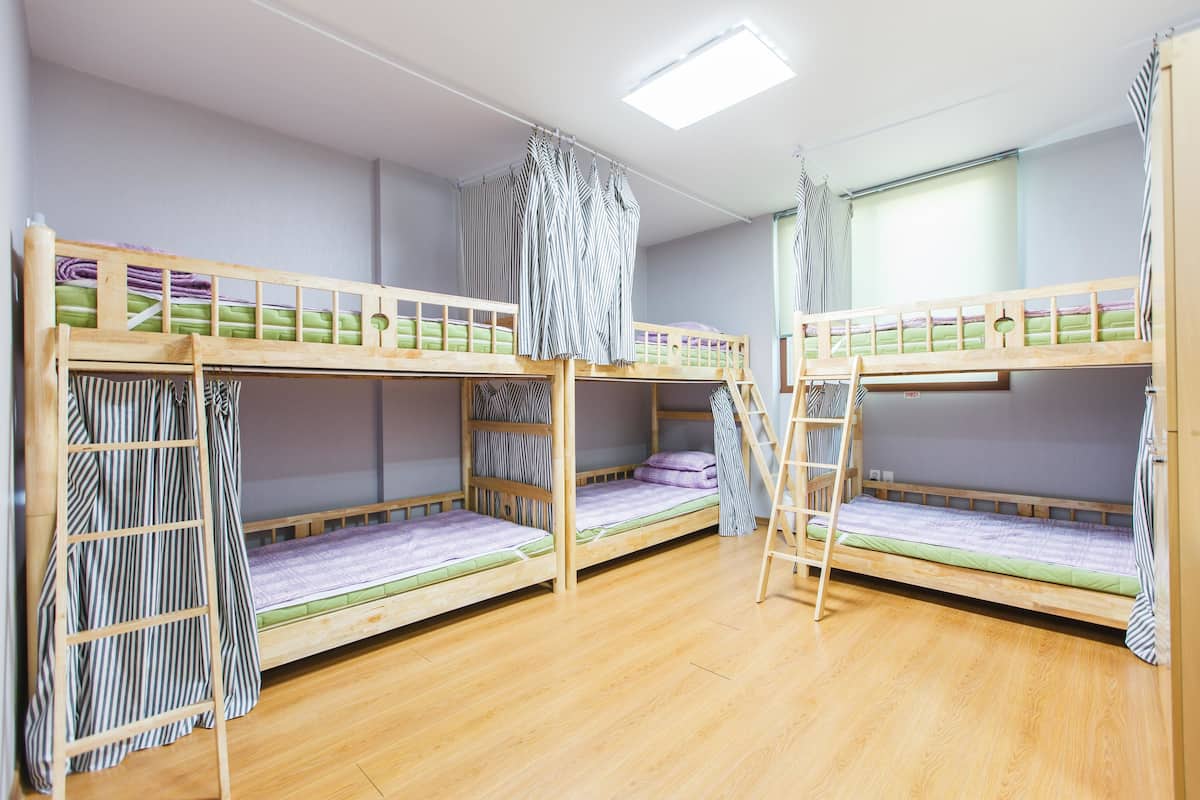 A room with three bunk beds, wooden flooring, and a skylight.