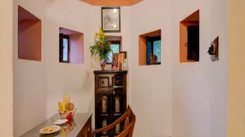 A dining area with a wooden table and chairs, a small cabinet, and a vase with flowers.