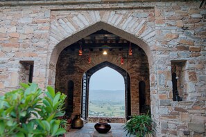 An arched stone doorway leading to a view of a valley. - Fort Dadhikar, Alwar (Alwar)