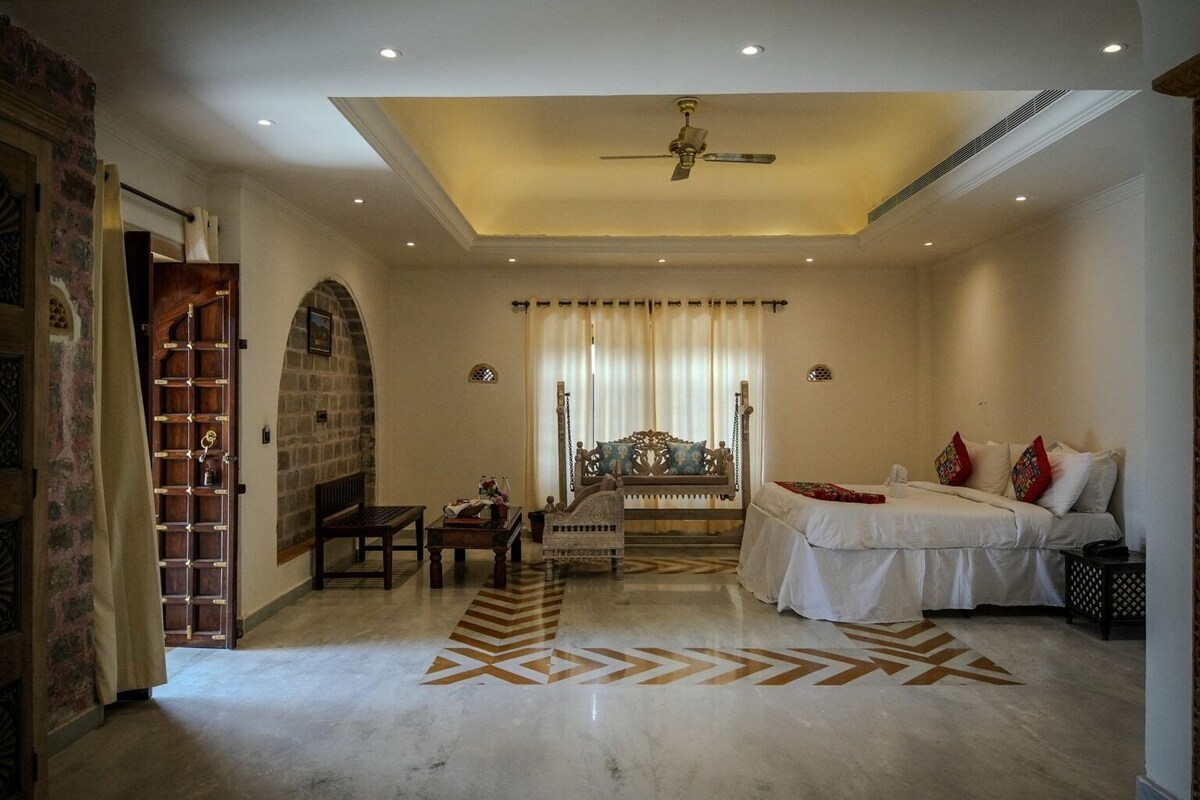 A bedroom with a bed, a sofa, a desk, and a chair.