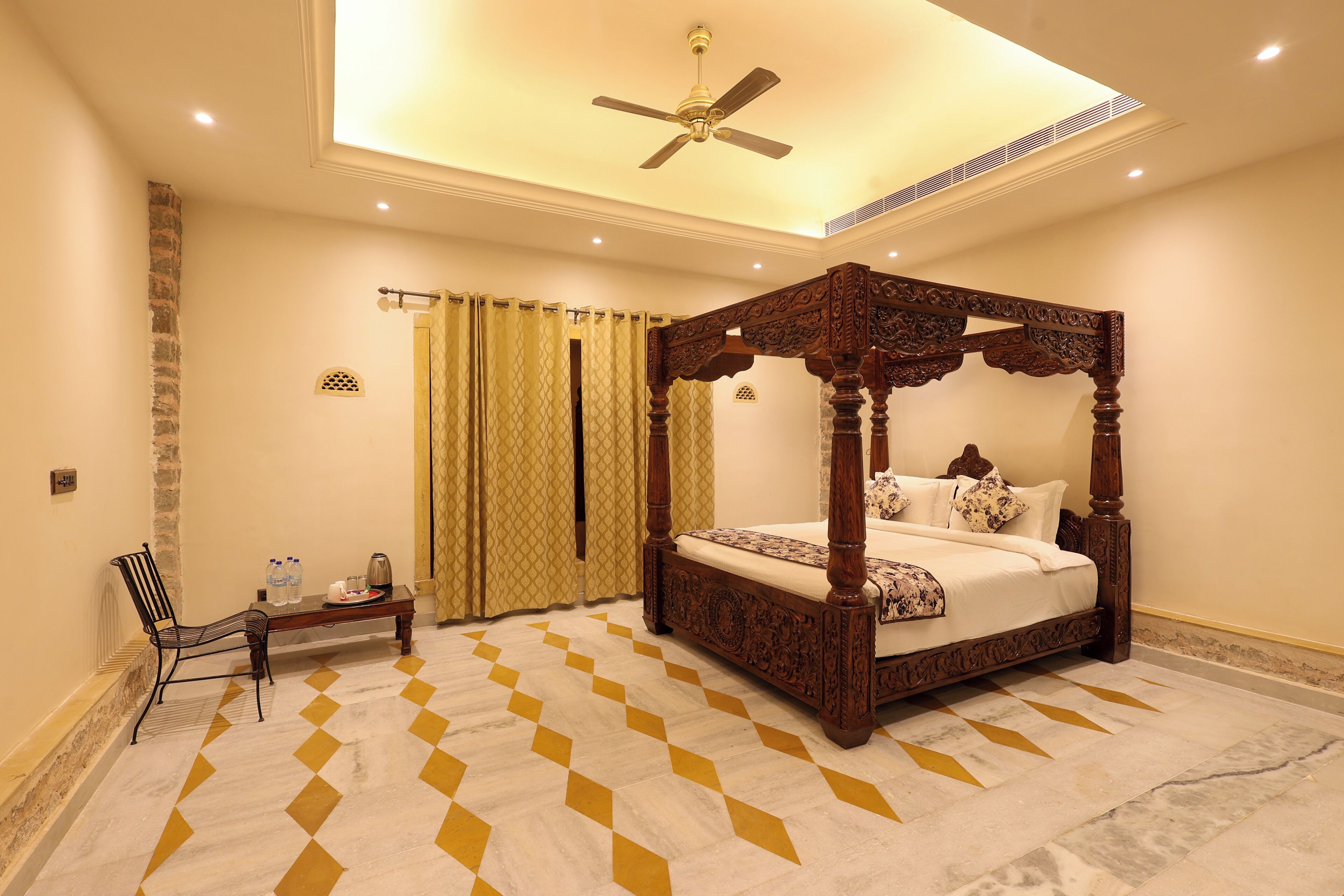 A four-poster bed with a wooden frame, a ceiling fan, and a checkered floor pattern.