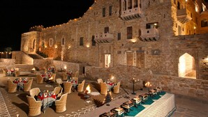 A historic stone building with outdoor seating and tables, illuminated by string lights. - Fort Dadhikar, Alwar (Alwar)