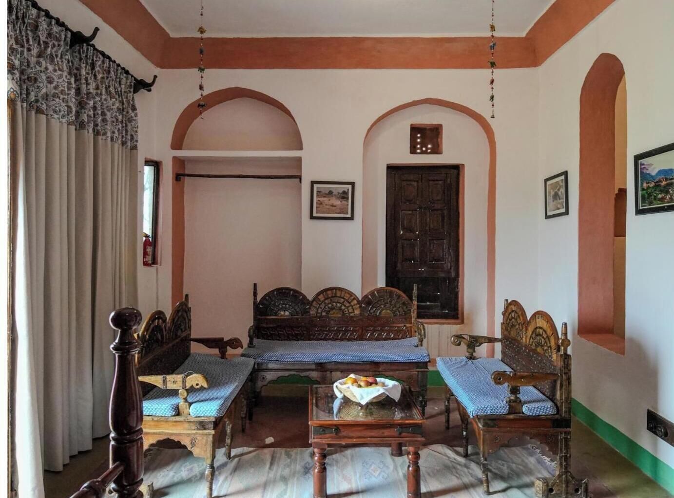 A traditional room with a wooden sofa set, a small table, and a bed with a headboard.