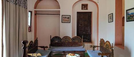 A traditional room with a wooden sofa set, a small table, and a bed with a headboard.
