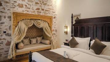A bedroom with a stone wall, a canopy bed, a wooden headboard, and a bedside table with a lamp.