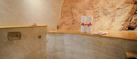 A bathroom with a marble wall, a toilet, and a sink area with towels.