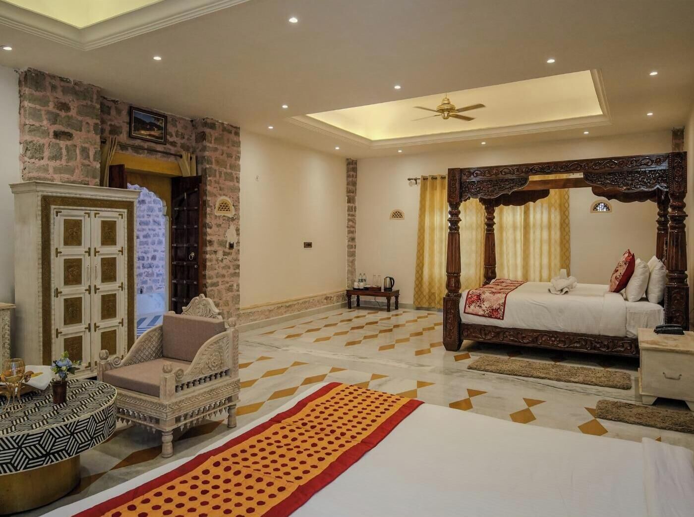 A bedroom with a four-poster bed, a sofa, a cabinet, and a patterned rug.