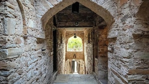 A stone corridor with an arched entrance leading to a room with a window. - Fort Dadhikar, Alwar (Alwar)