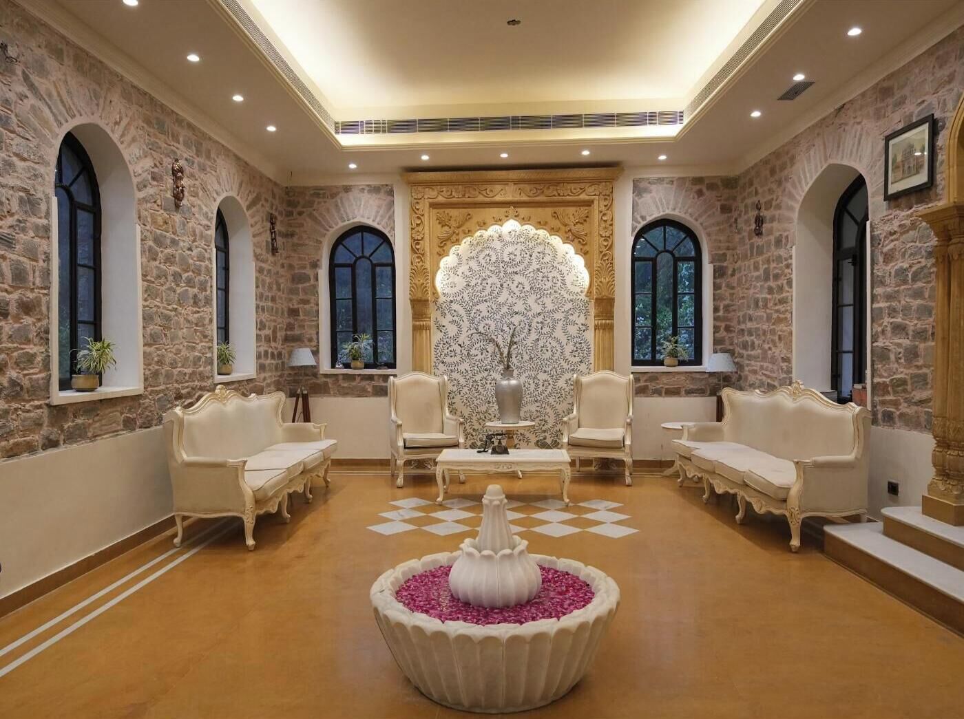 A luxurious room with stone walls, arched windows, and ornate furniture.