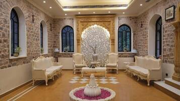 A luxurious room with stone walls, arched windows, and ornate furniture.