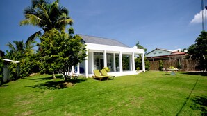 Ein modernes Haus mit überdachter Terrasse, gepflegtem Rasen und Holzzaun.