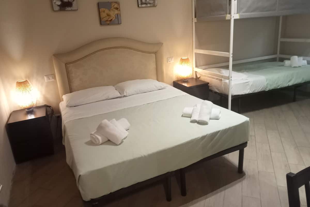 A hotel room with a large bed, a smaller bed, two bedside tables with lamps, and artwork on the walls.