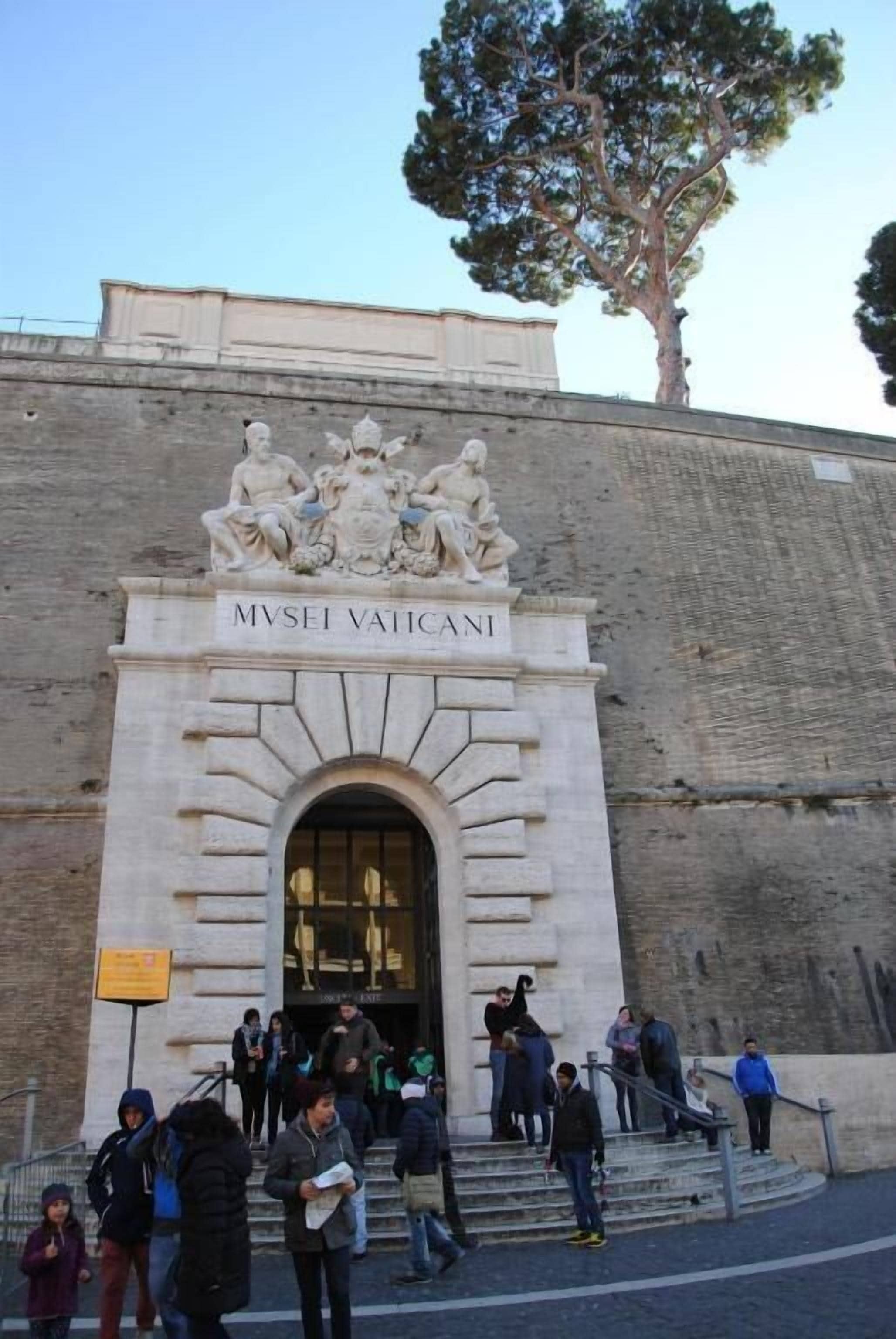 The entrance to the Museo Vatikano with a large arched doorway and a statue above.