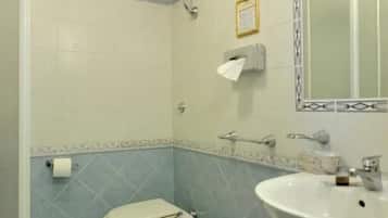 A bathroom with two toilets, a bidet, a sink, and a mirror.